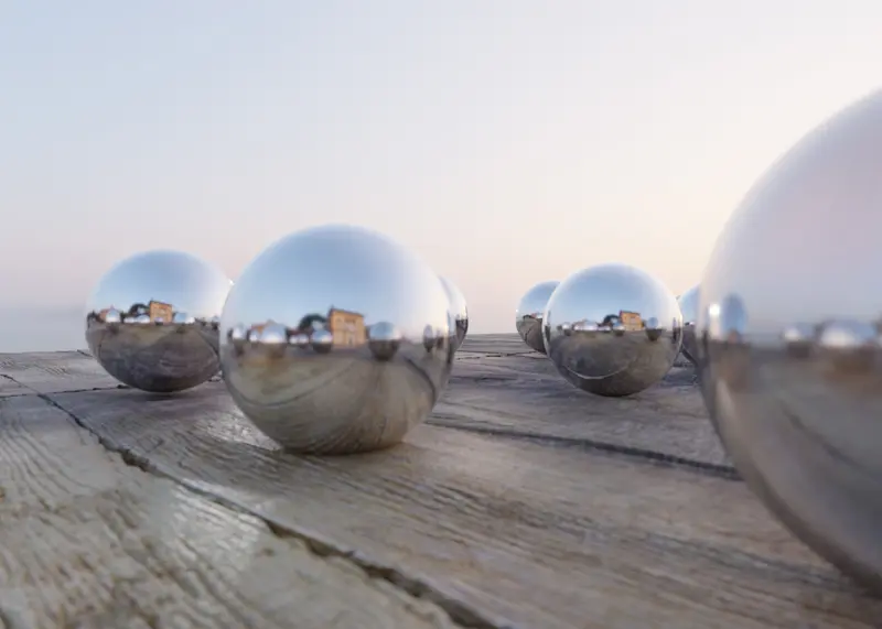 Metallkugeln auf einer Holzfläche, die ihre Umgebung aus unterschiedlichen Blickwinkeln reflektieren – persönliche Herangehensweise und Perspektivenwechsel in der Arbeit einer Klinischen Psychologin in Villach und online